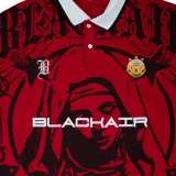 Camisa deportiva roja con cuello polo blanco y puños con ribete blanco. Presenta un estampado con motivos religiosos, logos y tipografías en negro.