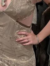 Vestido corto de lentejuelas color verde oliva, con escote en V, breteles finos cruzados en la espalda, cut-outs laterales y volado en el ruedo.