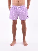 Short de baño lila con estampado de palmeras y veleros en blanco, con cintura elástica y cordón ajustable.