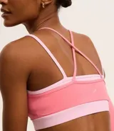 Top deportivo de microfibra color rosa con breteles finos y diseño de superposición bicolor.