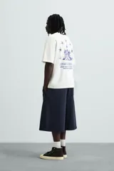 Camiseta blanca de corte holgado con cuello redondo y mangas cortas. Estampa en el pecho con la frase "Create a Narrative" en azul.
