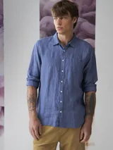 Camisa azul de lino con botones blancos, manga larga y bolsillo en el pecho.