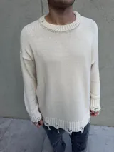 Sweater beige de hilo con cuello redondo y terminaciones rotas.