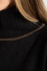 Sweater negro de tejido grueso con cuello alto acanalado. Presenta una franja decorativa en las mangas y el cuello en hilo marrón con brillo (lurex).