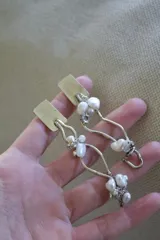 Aros colgantes de alpaca color plateado con perlas de río blancas.