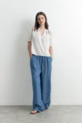 Blusa blanca de manga corta con escote en V y bordados florales en los hombros.