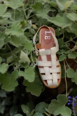 Sandalias de cuero marrón con tiras entrecruzadas y hebilla dorada al tobillo.