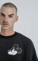 Buzo negro de frisa 100% algodón, de calce oversize y cuello redondo. Estampado pequeño en el frente del personaje Mickey Mouse enojado.