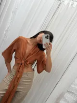 Top color ladrillo, confeccionado en lino, con mangas amplias y lazo versátil para atar al frente o atrás.