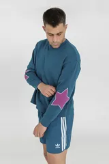 Buzo azul petróleo de corte holgado con cuello redondo y manga larga. Estampa de estrella fucsia en el antebrazo.