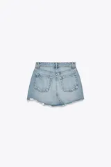 Minifalda de denim azul con tiro medio, trabillas, cinco bolsillos, roturas y bajo desflecado.