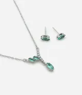Conjunto de collar con cadena plateada y dije con tres zirconias ovaladas color aguamarina y aros tipo botón con zirconias aguamarina.