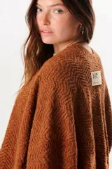 Ruana color tostado de tejido de punto con diseño de espiga y flecos en el borde inferior.