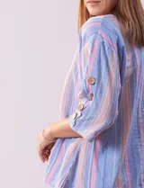 Blusa de algodón a rayas verticales en tonos celeste, rosa y blanco. Tiene cuello redondo con escote en V y abertura con botones de madera. Las mangas son 3/4 con aplique de botones.
