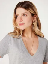 Remera gris de corte clásico, con cuello en V y mangas cortas.