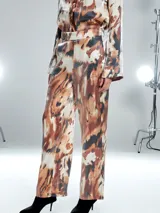 Pantalón de vestir con estampado abstracto en tonos marrones, negros y blancos.