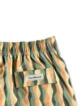 Short de baño blanco con estampado de hojas de palmera en tonos verde, rojo y amarillo.