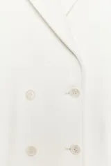 Abrigo largo color crudo de Zara Woman Collection, con cuello solapa, manga larga, bolsillos de vivo con solapa y cierre frontal cruzado con botones.