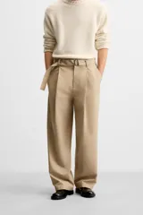 Pantalón negro de corte ancho con cinturón de tela con hebilla metálica y pliegues frontales.
