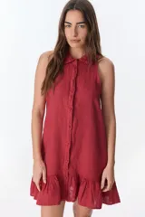 Vestido corto color ladrillo, sin mangas, con cuello camisero con volados, abotonado al frente y falda con volados.
