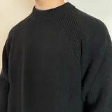 Sweater verde oliva de tejido grueso con cuello alto.