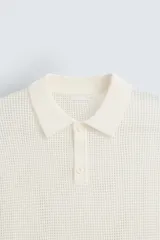 Polo blanco de punto tejido con estructura calada, corte regular fit, cuello solapa con abertura frontal y manga corta.