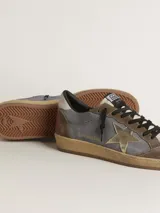 Championes Golden Goose modelo Ball Star, confeccionados en cuero color gris, marrón y beige, con estrella dorada en el lateral, detalles en rojo en el talón y suela de goma color caramelo.