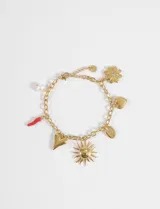 Pulsera de cadena eslabonada de acero quirúrgico color dorado, con múltiples dijes colgantes: sol con rostro, corazón liso, flor con cristal central, corazón texturado, caracol marino, y un cuerno rojo (cornicello). También incluye una perla blanca colgante.