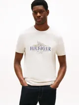 Remera de hombre Tommy Hilfiger color crema, de corte regular y cuello redondo. Presenta un estampado con el logo de la marca y motivos tropicales en el pecho.