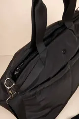 Cartera tipo bolso color verde militar, con asas fijas y correa desmontable, múltiples bolsillos exteriores e interiores.