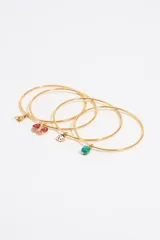 Set de cuatro pulseras doradas con dijes colgantes: abeja, mariposa, mariquita y piedra verde.