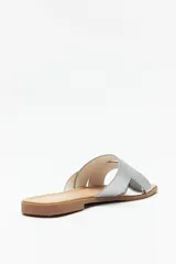 Sandalias bajas plateadas con tiras anchas cruzadas en el empeine y suela plana color marrón.