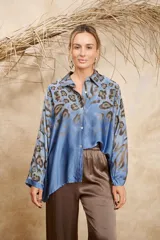 Camisa celeste con estampado animal print en tonos marrones, de seda, con cuello camisero, cierre frontal con botones y mangas 3/4.