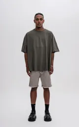 Remera de manga corta color verde militar, con calce extra oversize y un recorte horizontal que atraviesa el pecho y la espalda.