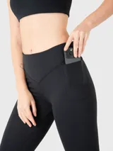 Calza deportiva negra con corte a la altura del tobillo, cintura alta con diseño en V y bolsillos laterales.