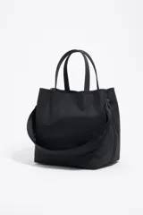 Bolso de mano Bimba y Lola modelo Chihuahua L, color marrón, con doble asa de mano y asa bandolera de tejido. Cierre con botón de presión, logo metálico y acabados plateados.