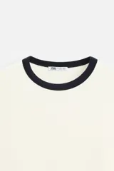Camiseta azul marino de corte recto, con cuello redondo y mangas cortas. Presenta ribete blanco en cuello y mangas.