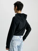 Buzo cropped negro de punto milano con capucha y mangas largas. Tiene puños de canalé y bajo elástico. El logo de Calvin Klein Jeans está bordado en la capucha.