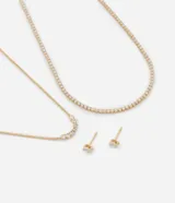 Conjunto de collar y aros dorados con detalles de zirconia. Incluye un collar corto con cadena de eslabones y dije de circonias, un collar largo con dije de circonias en forma de media luna y un par de aros tipo botón con circonias.