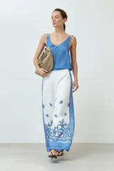 Pantalón blanco con estampado floral y guarda geométrica en tonos de azul.