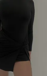 Minivestido negro de mangas largas y cuello alto, con nudo drapeado en la falda y abertura lateral.