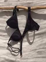 Conjunto de bikini blanco con textura, compuesto por un corpiño de triángulo fijo con breteles regulables y almohadillas desmontables, y una bombacha vedetina con frunce elástico en los costados.