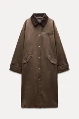 Trench marrón encerado con cuello solapa combinado en pana, manga larga, trabillas y pinza en la espalda, bolsillos delanteros con solapa y botón a presión, y cierre frontal con botones a presión.