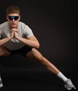 Bermuda deportiva masculina de poliéster reciclado certificado RCS, color negro, con cintura elástica y lazo ajustable. Presenta un estampado abstracto en tonos claros en la parte superior delantera.