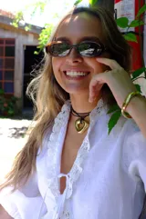 Collar con dije dorado irregular con agujero central, colgando de cordón negro ajustable.