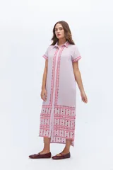 Vestido largo de lino en color celeste, con cuello camisero, manga corta y cierre frontal con botones. Presenta bordados decorativos en contraste en la pechera y en el ruedo.