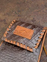 Cartera bandolera porta celular color marrón con textura croco y correa fina.