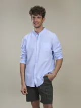 Camisa celeste de lino con cuello mao, manga larga con puños abotonados, cierre frontal con botones y bolsillo de parche en el pecho.