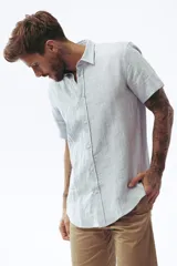 Camisa blanca de manga corta con cuello clásico y cierre frontal con botones.
