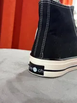 Zapatillas de lona blancas de caña alta con cordones y puntera de goma. Logo de durazno engomado en la base y en la cara interna.